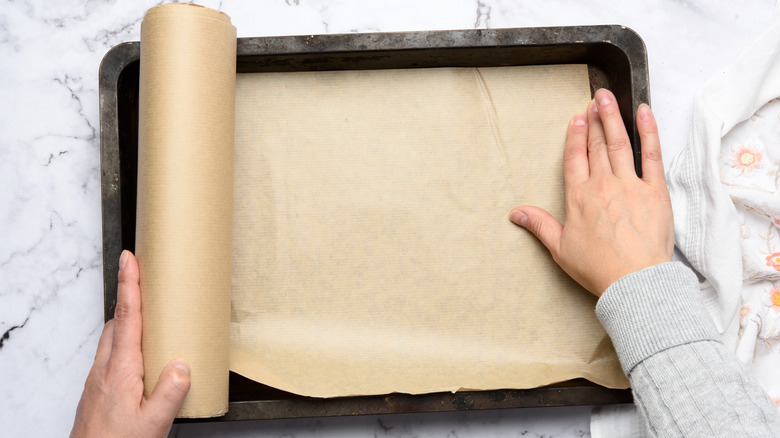 Hands placing parchment on sheet pan