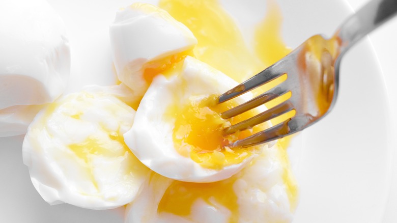 poached eggs beign pierced