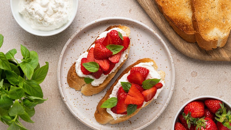 Toasted bread with ricotta cheese, strawberries, and basil leaves