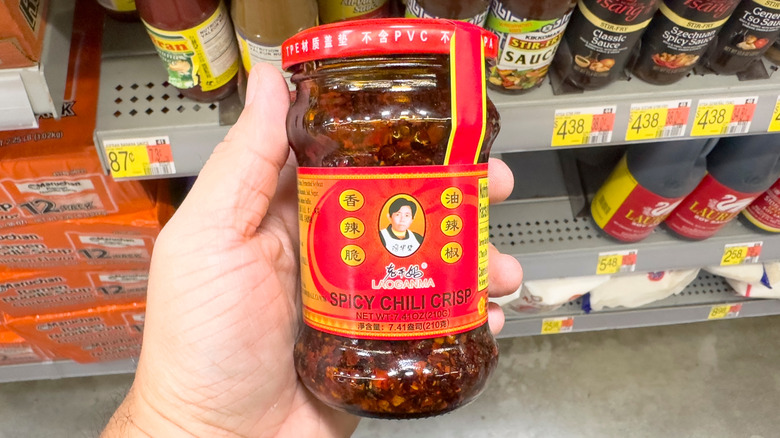 Hand holding jar of Chinese Lao Gan Ma spicy chili crisp condiment at the grocery store