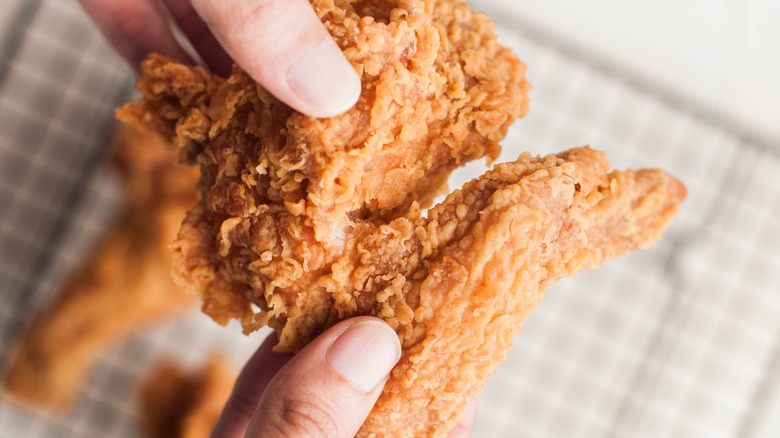 handing holding fried chicken