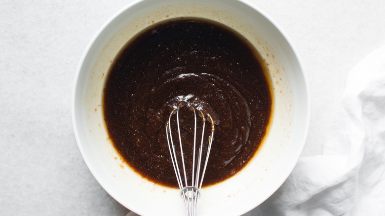 Cocoa powder is whisked into a liquid in a white bowl