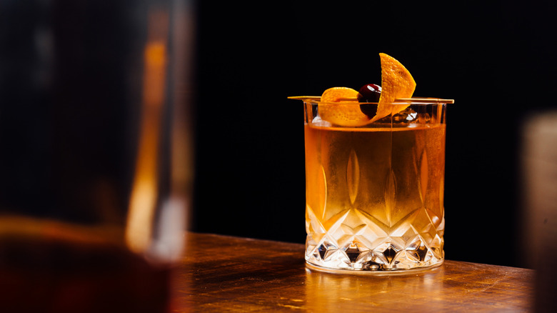 Brownish-colored cocktail in rocks glass with an orange peel twist