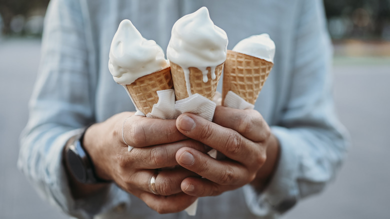 Person holding three melting ice cream cones