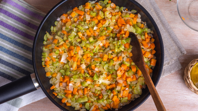 Minced celery, onions, and carrots browning in a pan, a classic soffritto