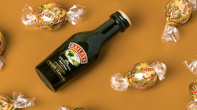 A bottle of Baileys chocolate liqueur beside pieces of candy