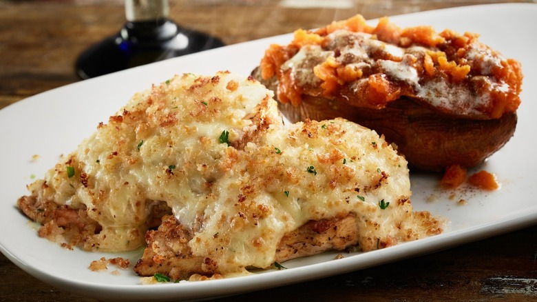 LongHorn Steakhouse's parmesan crusted chicken and a loaded baked potato on a white plate