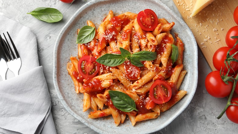 Penne pasta dressed with basil, cheese, and tomatoes