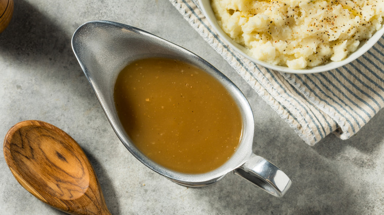 Brown gravy in a metal gravy boat.