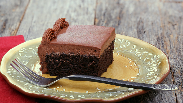 A slice of chocolate sheet cake sits on a plate