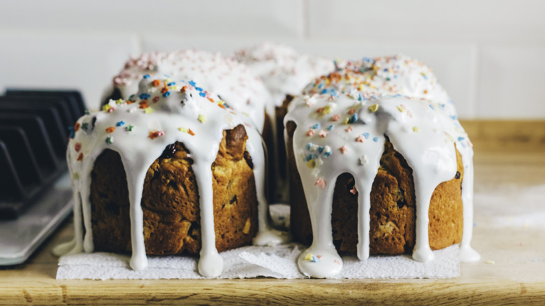 muffins with a runny glaze and sprinkles on a counter