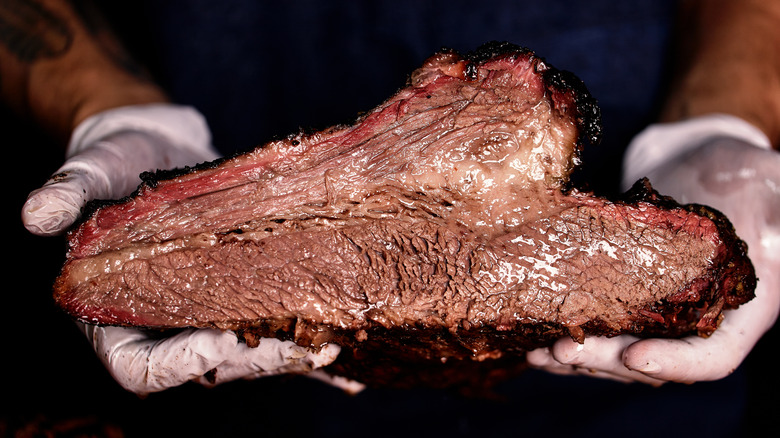 a person holding a freshly cooked brisket