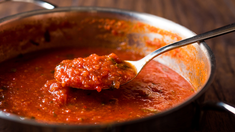 spoon of tomato sauce over a pot of tomato sauce