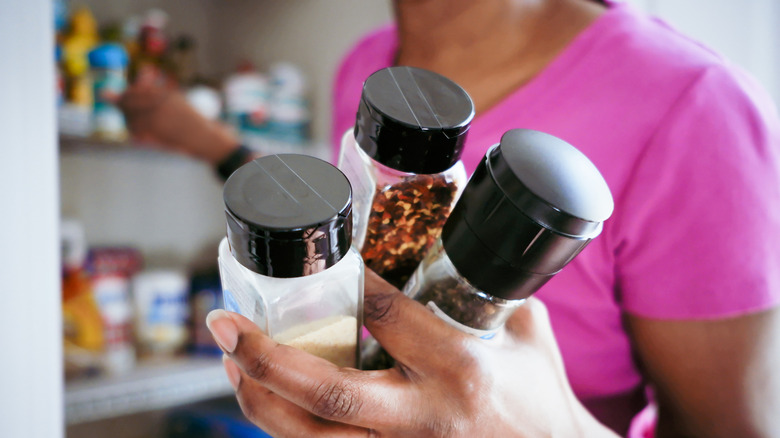 Close-up of woman grabbing spices from pantry