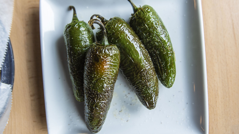 Roasted green jalapenos on a white plate