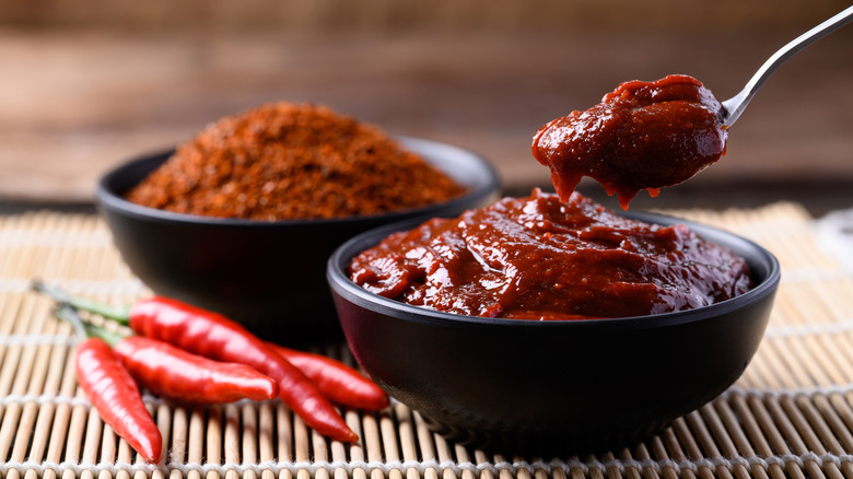 Spoonful of gochujang sauce served in a black bowl