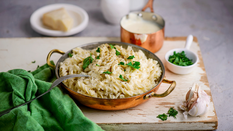 Rotini pasta with Alfredo sauce in a pan surrounded by ingredients