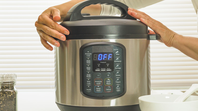 person closing pressure cooker lid on counter