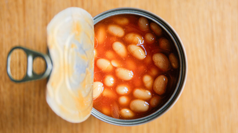 A top view of a can of beans with the metal lid peeled back