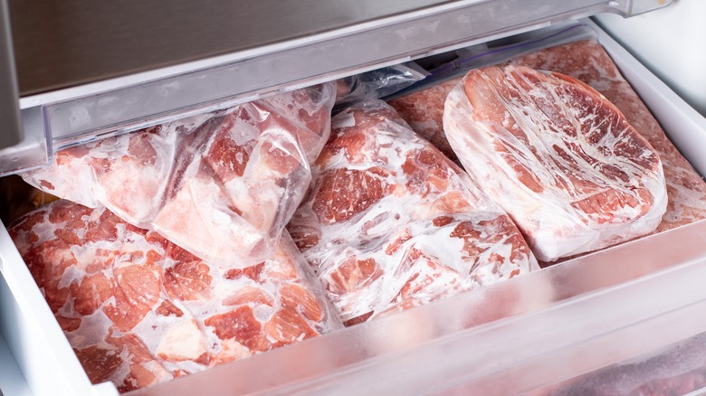 Multiple slabs of frozen pork individually wrapped in plastic sit in the freezer