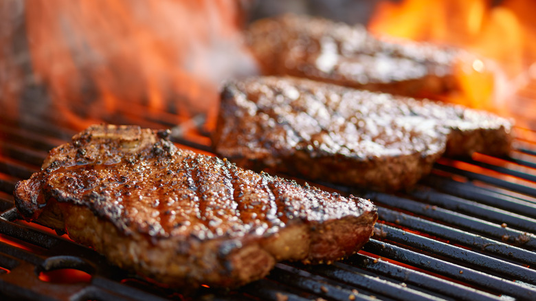 Steaks cooking on a grill.