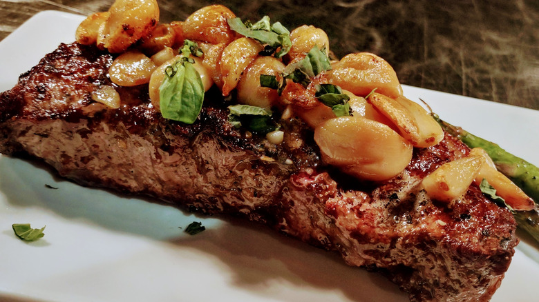 A prime New York strip steak topped with roasted garlic and basil