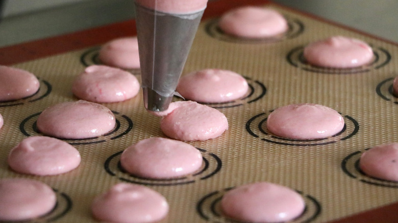 Macarons being piped onto baking mat