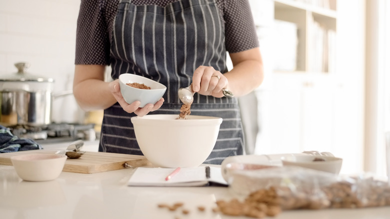 Person adding cocoa powder to bowl