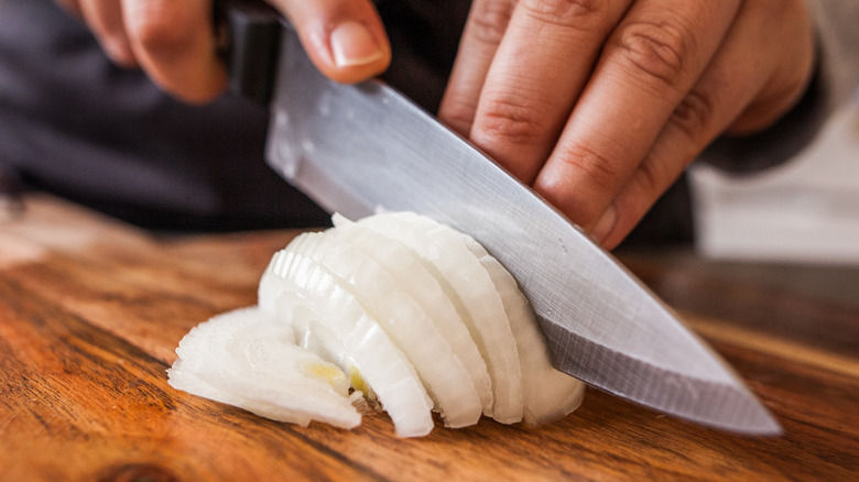 A person chopping onions with a sharp knife