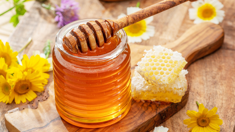 Jar of honey next to pieces of honeycomb