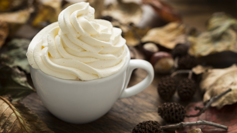 whipped-cream-topped hot drink and fall foliage