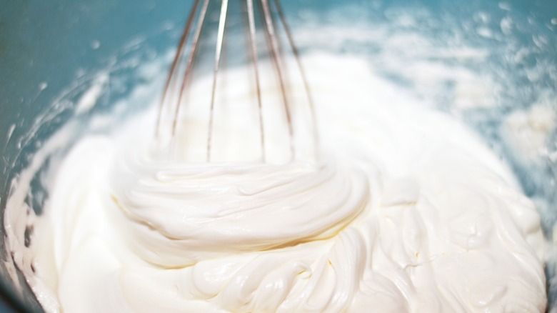 whisk in mixing bowl of cream being whipped
