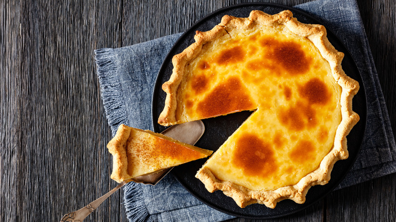 Indiana custard cream pie on black plate on dark wood table, with cake shovel