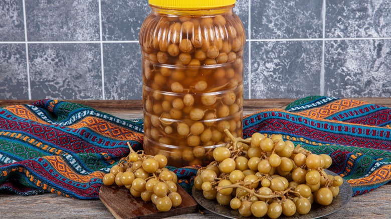 A plate of pickled grapes, with the jar behind them.