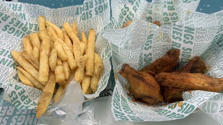 Order of wings and French fries next to each other in branded Wingstop baskets