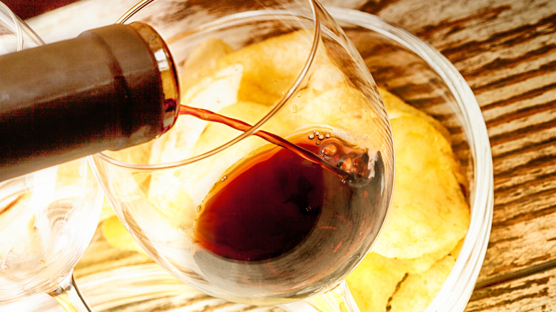 Red wine pouring into glass with chips in background