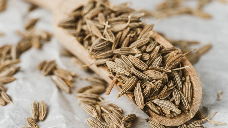 a wooden scoop filled with caraway seeds