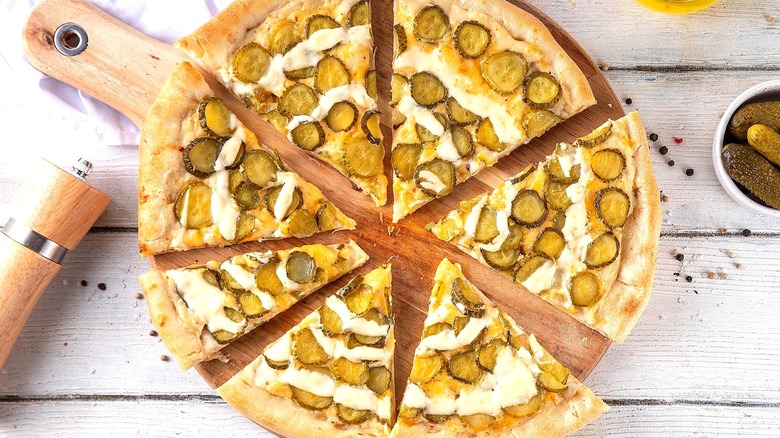 Baked sliced pizza with a creamy sauce and pickle coins