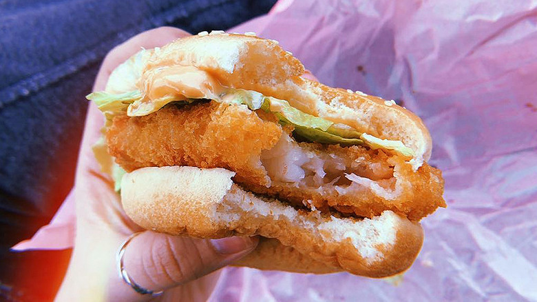 Hand holding an Ebi Shrimp Filet-O burger from McDonald's Japan with bite taken to show inside