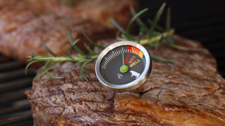 Checking the internal temperature of steaks on a grill