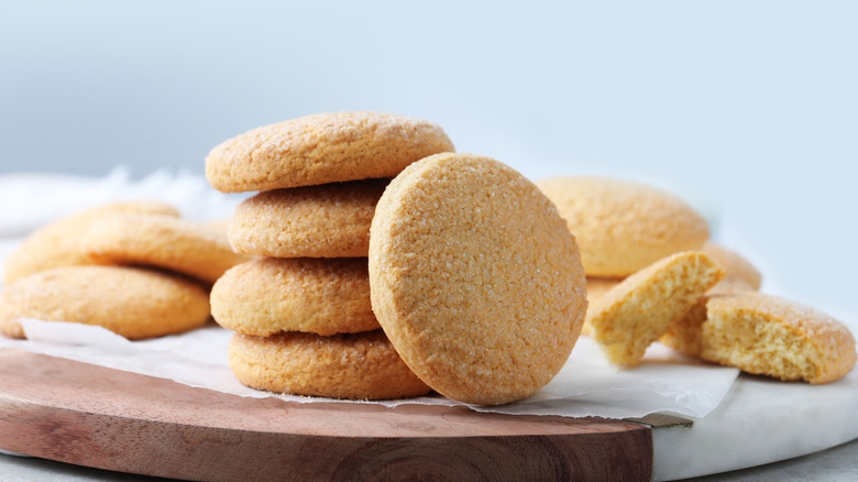 A stack of sugar cookies on a wooden board.