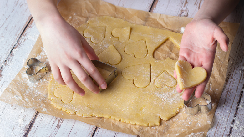 Cutting sugar cookies out of rolled dough.