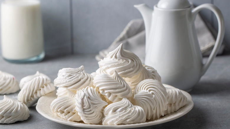 whipped meringues sit in pretty piles next to a white tea pot