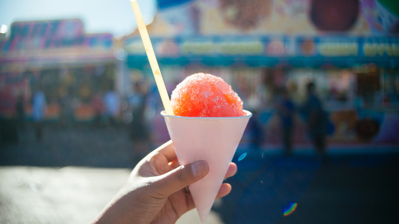 Snow cone in a paper cup with yellow straw