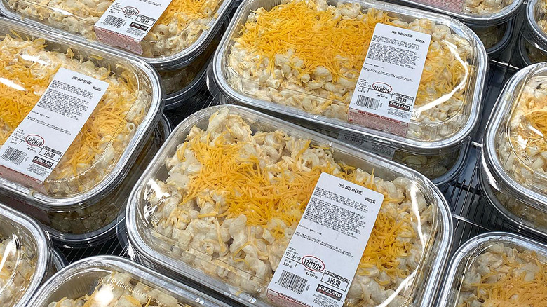 Stacked Costco prepared mac and cheese containers in refrigerated display case