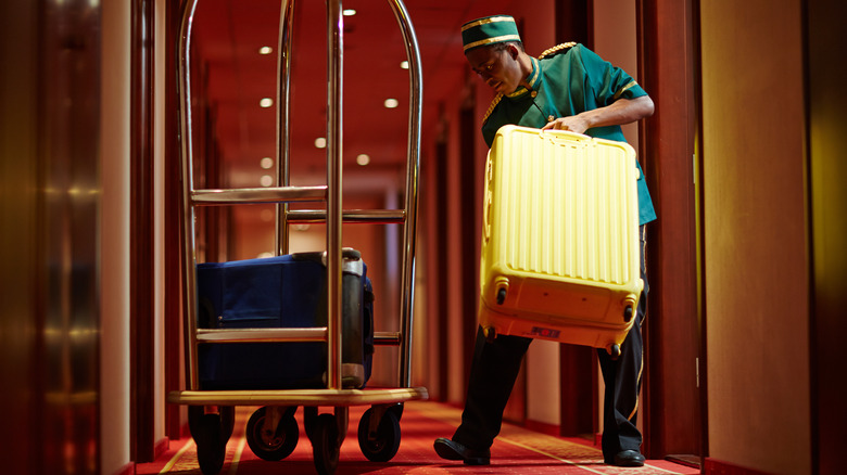 Hotel porter lifting bag off trolley