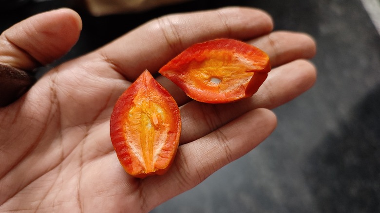 A sliced peanut butter fruit in person's palm