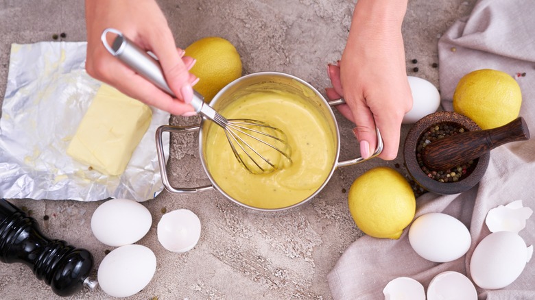 Hollandaise sauce being whisked by hand in a pan