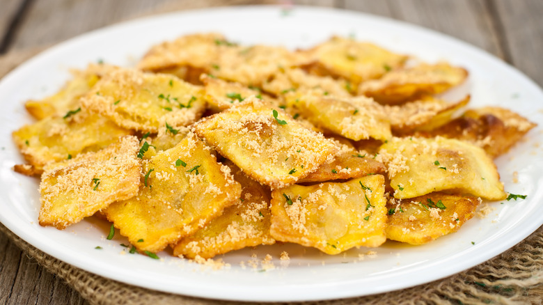 Fried ravioli with breaded garnish on white plate