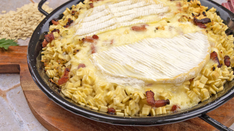 croziflette topped with reblochon cheese in a black pan